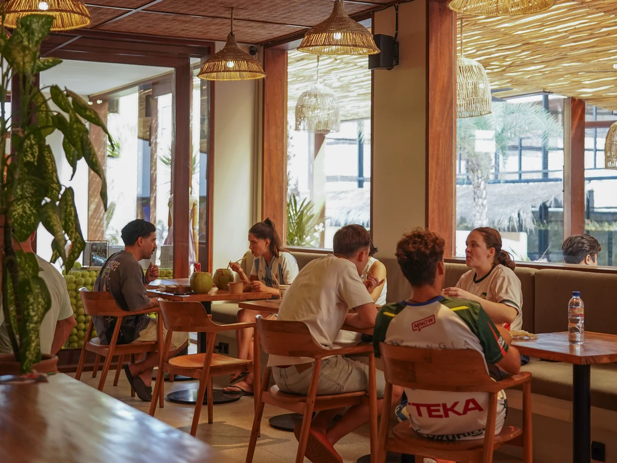 Players sharing a relaxed meal with fresh coconuts in the sunlit clubhouse